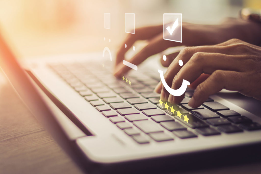 Businesswoman pressing face emoticon on the keyboard laptop / Customer service evaluation concept.