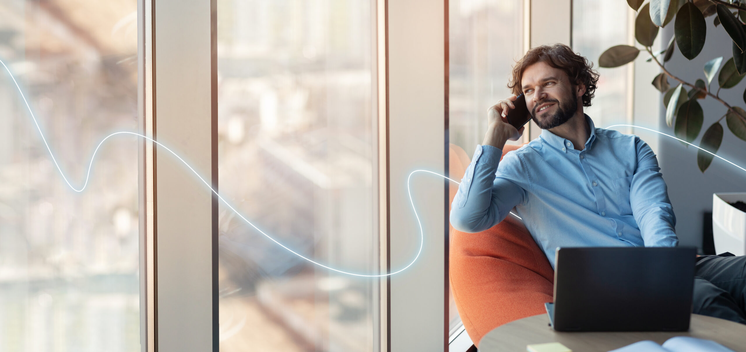 Smiling confident european millennial businessman with laptop calls by phone, looks out the window in office interior with abstract line, empty space. Work, professional and business communication